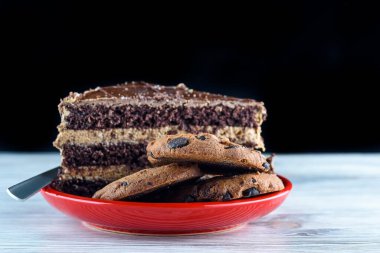 Bir parça çikolatalı kek ve üzerinde çikolata olan kurabiyeler.