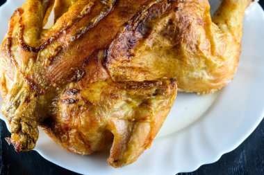 Kızarmış tavuk, ahşap bir arka planda beyaz bir tabakta.