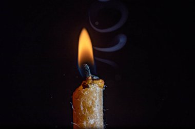 Yanan bir mumun alevi karanlık bir arka plana karşı.