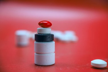 Kırmızı arkaplanda tıbbi tabletlerden oluşan bir sütun