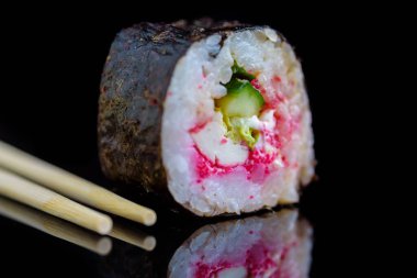 Suşi rulosu koyu bir arkaplanda izole edilmiş..