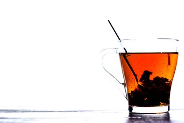 Beyaz arka planda şeffaf bir fincanda çay