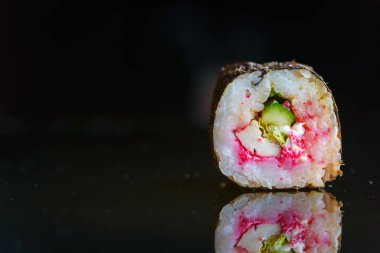 Suşi siyah ayna arka planında yuvarlanıyor..