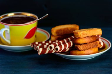 Koyu arkaplanda kahve fincanında waffle ruloları.