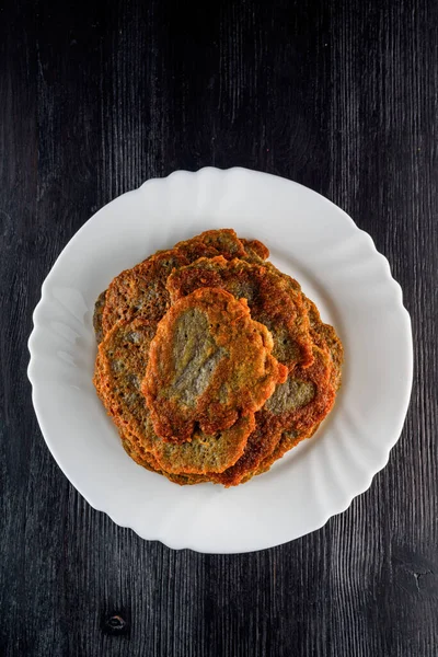 Tahta bir taşrada, beyaz bir tabakta bir yığın patatesli krep.