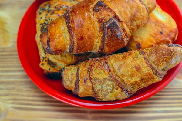 Ahşap bir arka planda kırmızı bir tabakta kruvasanlar.