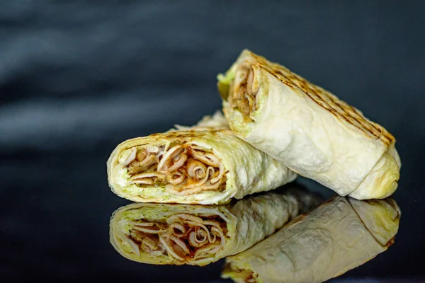 Shawarma with chicken and cabbage on a dark background.