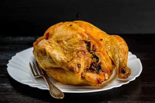 Beyaz tabakta kızarmış tavuk, siyah ahşap arka planda.