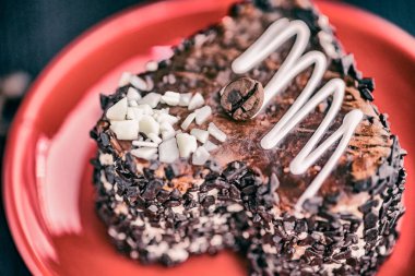 Kırmızı tabakta kalp şeklinde bir dilim çikolatalı pasta..