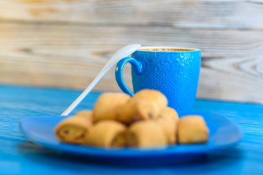 Tahta bir fonda kremalı bisküviler, bir fincan kahve..