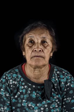 Karanlık bir arka planda yaşlı bir kadının dramatik portresi