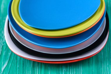 Yeşil ahşap arka planda bir yığın renkli tabak..