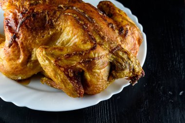 Kızarmış tavuk, ahşap bir arka planda beyaz bir tabakta.