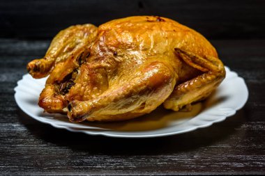 Beyaz tabakta kızarmış tavuk, siyah ahşap arka planda.