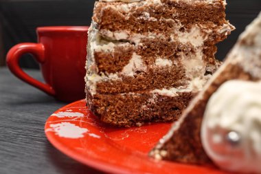 Kremalı ekşi pasta ve kırmızı bardakta taze kahve.