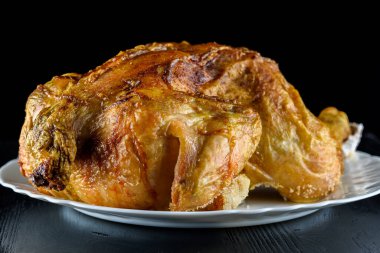 Kızarmış tavuk, ahşap bir arka planda beyaz bir tabakta.