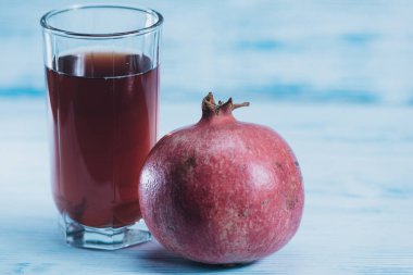 Tahta zemin üzerinde nar suyu ve nar meyveleriyle dolu cam deney şişesi.