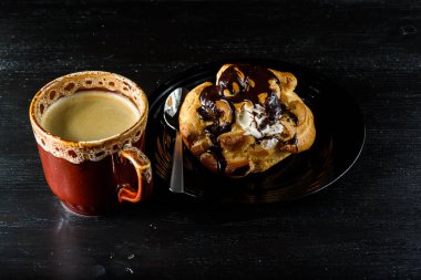 Bir kupa taze kahve ve siyah ahşap arka planda bir ekkin.