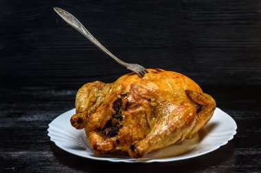 Beyaz tabakta kızarmış tavuk, siyah ahşap arka planda.