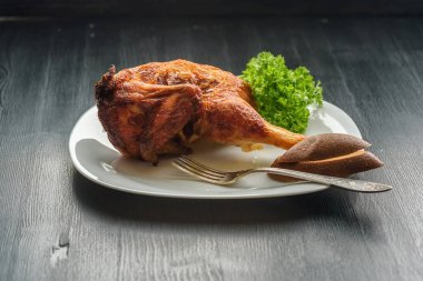 Koyu ahşap arka planda beyaz tabakta kızarmış tavuk.