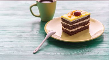 Üzerinde kiraz olan çikolatalı pasta ve tahta arka planda yakın plan çekilmiş bir fincan kahve..