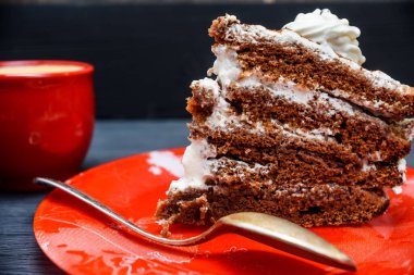 Kırmızı tabakta bir dilim lezzetli pasta ve D 'nin üzerinde taze kahve.