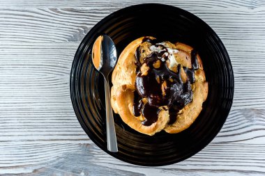 Tahta bir arka planda siyah bir tabakta çikolatalı ekler.