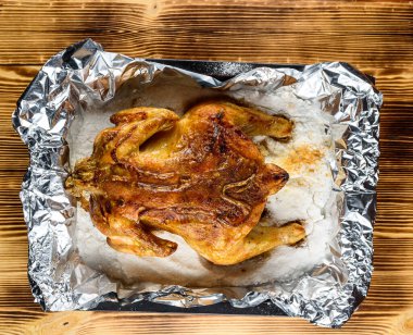 Kızarmış tavuk, ahşap bir arka planda beyaz bir tabakta.