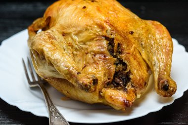 Beyaz tabakta kızarmış tavuk, siyah ahşap arka planda.