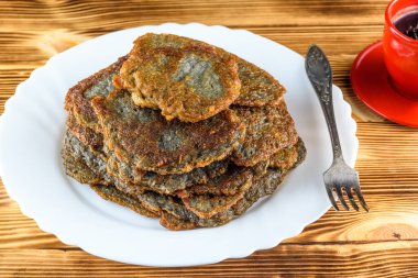 Tahta bir taşrada, beyaz bir tabakta bir yığın patatesli krep.