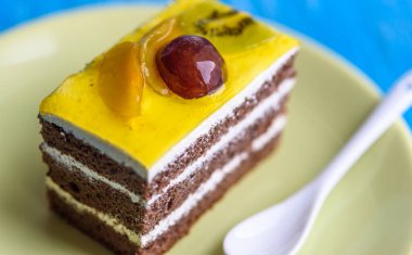 Üzerinde kiraz olan çikolatalı pasta ve tahta arka planda yakın plan çekilmiş bir fincan kahve..