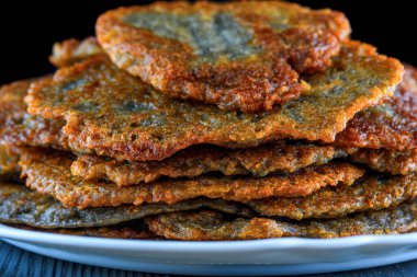 Tahta bir taşrada, beyaz bir tabakta bir yığın patatesli krep.