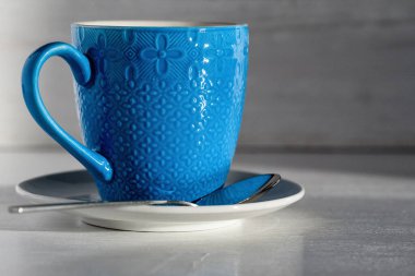 Açık ahşap arka planda mavi bir fincanda kahve.