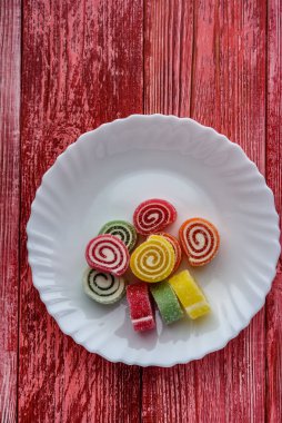 Beyaz bir tabakta kırmızı bir ağaçta çok renkli marmelat.