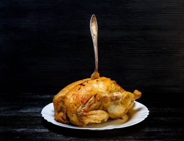 Beyaz tabakta kızarmış tavuk, siyah ahşap arka planda.