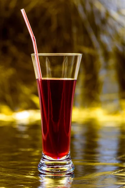金色の背景に赤いジュースのガラス — ストック写真