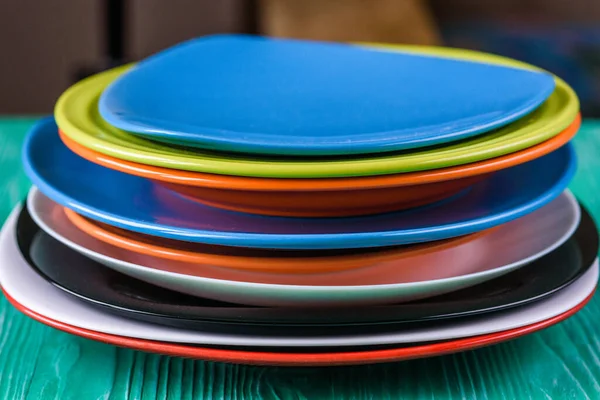 Yeşil ahşap arka planda bir yığın renkli tabak..