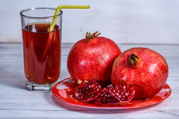 glass beaker with pomegranate juice and pomegranate fruits on a