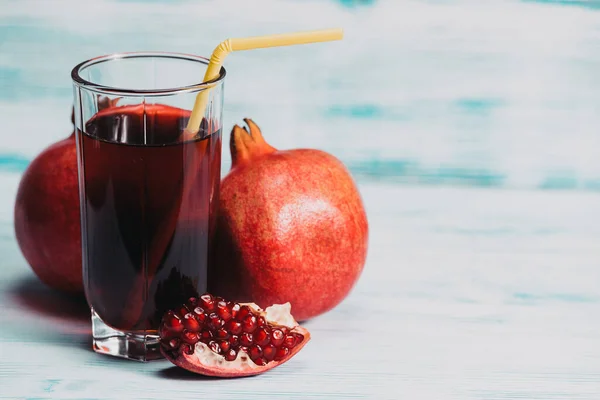 glass beaker with pomegranate juice and pomegranate fruits on wooden background