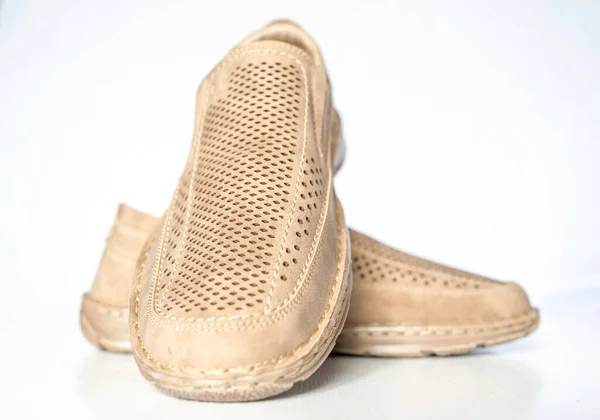 Men\'s beige leather shoes, models moccasins. Photographed close-up on a light background.