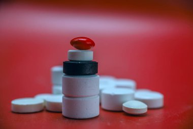 Kırmızı arkaplanda tıbbi tabletlerden oluşan bir sütun