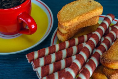 Koyu arkaplanda kahve fincanında waffle ruloları.