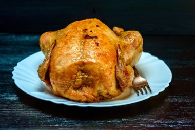 Beyaz tabakta kızarmış tavuk, siyah ahşap arka planda.