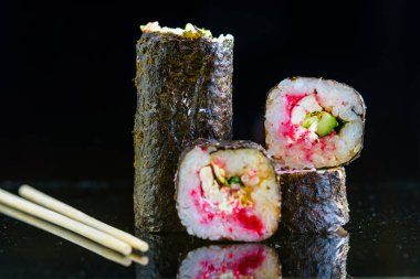 Suşi siyah ayna arka planında yuvarlanıyor..
