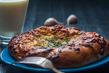 Sarımsak ve peynirli ekmek ve koyu ahşap arka planda bir bardak süt..