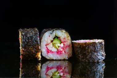 Suşi siyah ayna arka planında yuvarlanıyor..