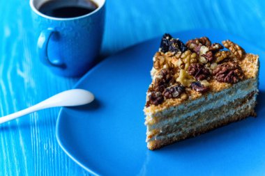 Cevizli kek dilimi, ahşap arka planda, turkuaz bir plakaya yakın plan çekilmiş..