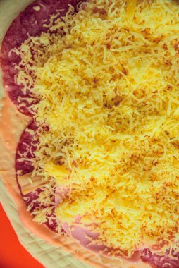 Kırmızı arka planda peynirli ve mantarlı çiğ pizza.