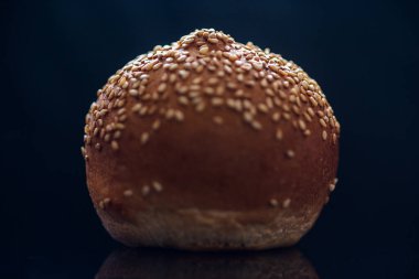 Siyah arkaplanda susam tohumlu çörek.