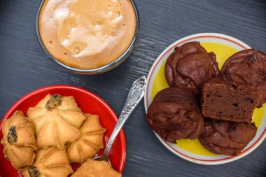 Tabakta çikolatalı kekler, kurabiyeler ve yakın plan çekilmiş bir fincan kahve..